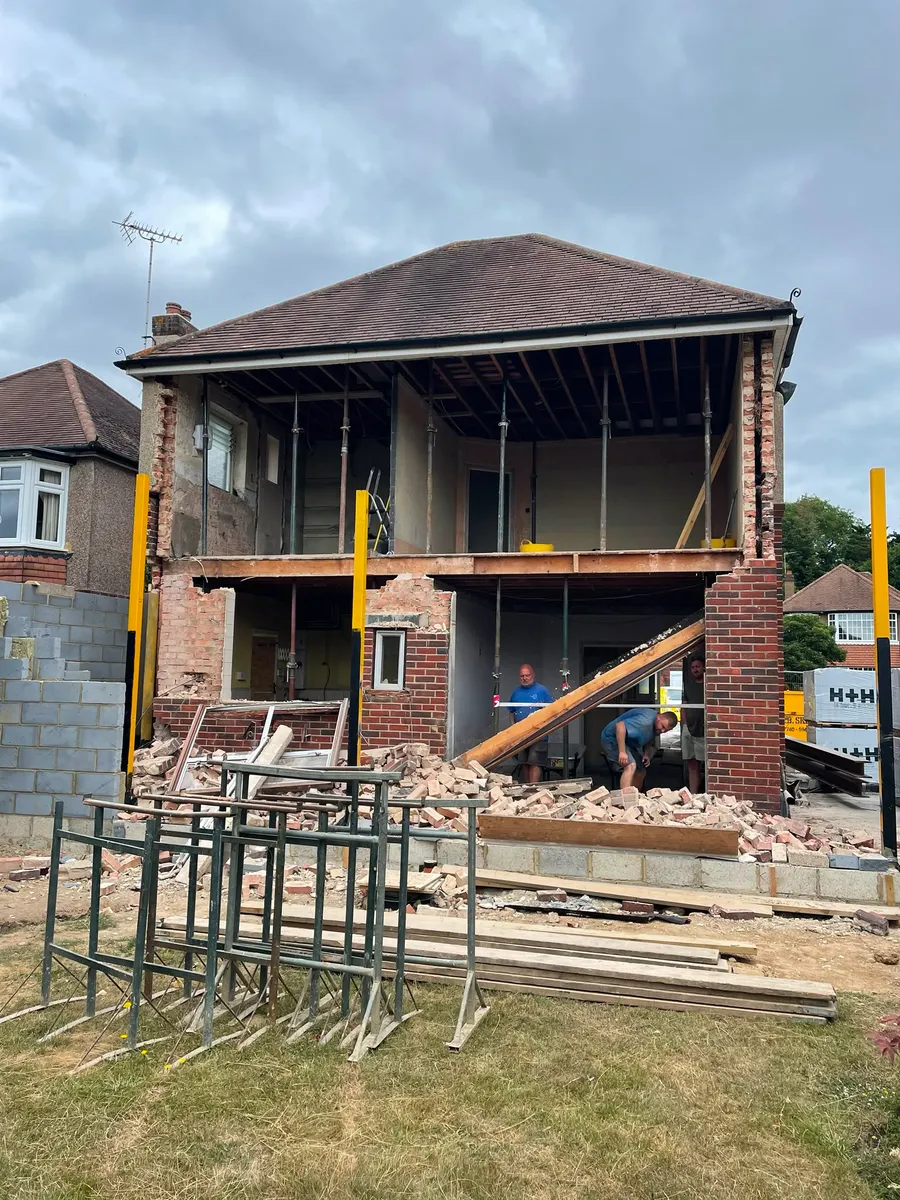 Double-storey extension under construction, with the existing brickwork opened up and steel props supporting the structure