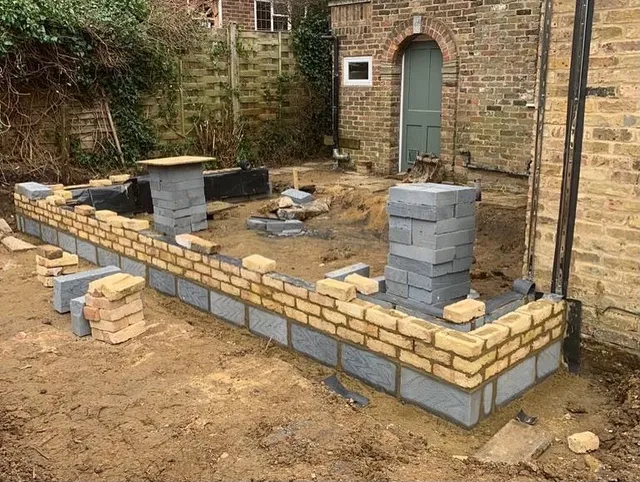 Brick and blockwork foundations for a new extension being built up around brick piers