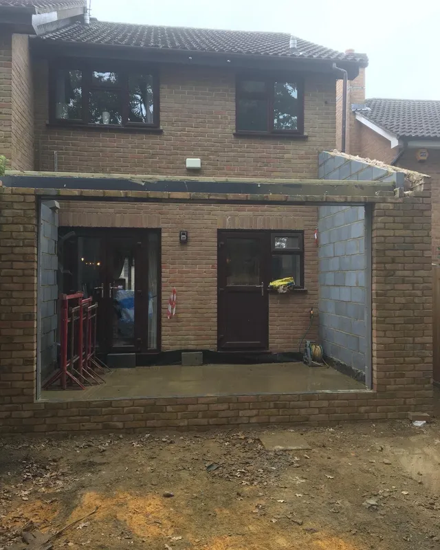 Rear extension shell nearing completion, with French doors, a back door and a new flat roof in place