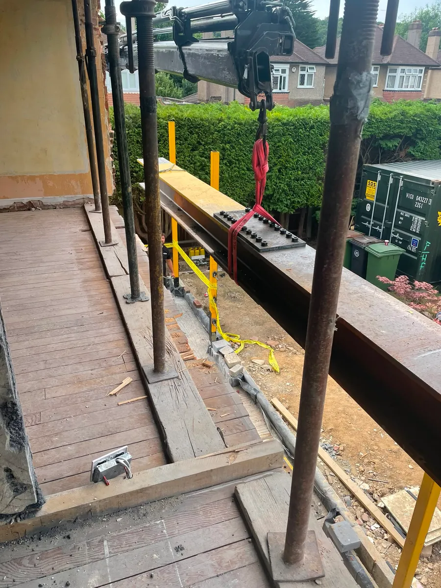 A structural steel beam being lifted into position to support a new house extension