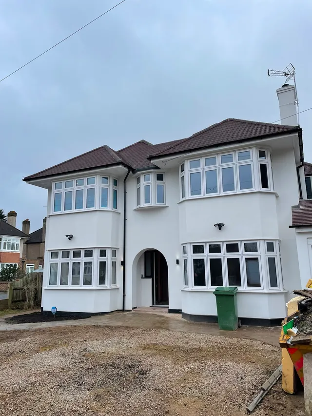 Completed house extension and renovation, rendered in white with replacement bay windows