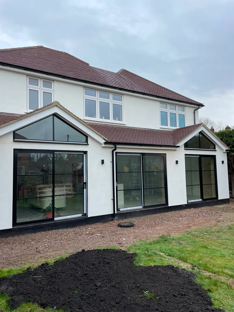 Completed rear extension with full-width black-framed sliding glass doors and a glazed gable end