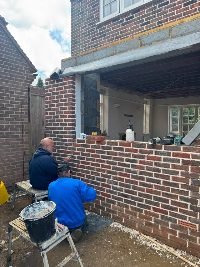 Local building specialists hand-pointing brickwork on a house extension